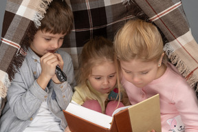 Kids reading a book in a hut