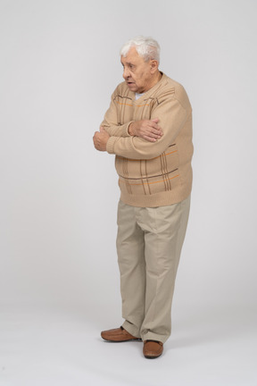 一位穿着休闲服的老人拥抱自己的侧视图