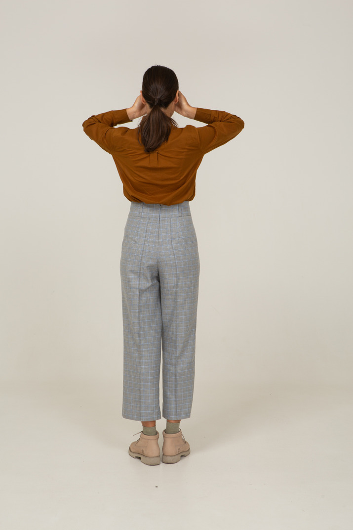 Back view of a young asian female in breeches and blouse hiding eyes