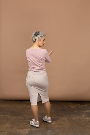 Вид сзади женщины в повседневной одежде, показывающей жест стоп