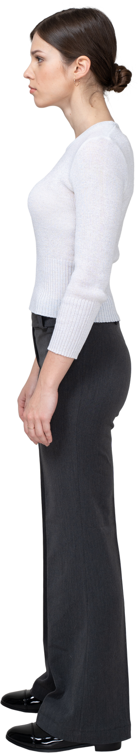 Side view of a young woman in office clothing standing still & knitting brows