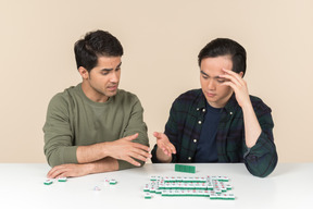 Amigos interraciais sentado à mesa e jogar o jogo de tabuleiro