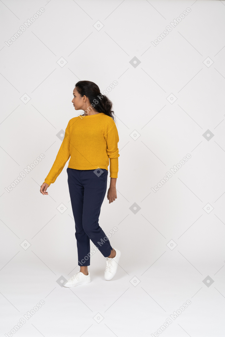 Front view of a girl in casual clothes walking forward and looking aside
