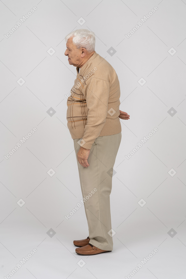 背中の痛みに苦しんでいるカジュアルな服を着た老人の側面図