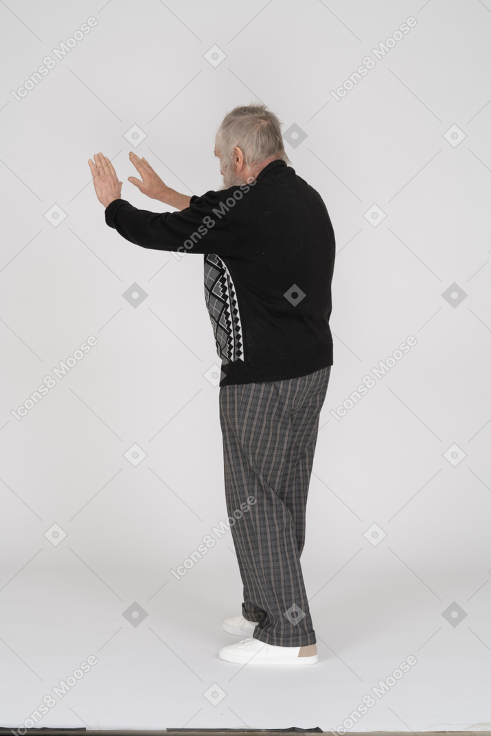 Вид сзади на старика, показывающего знак "стоп"