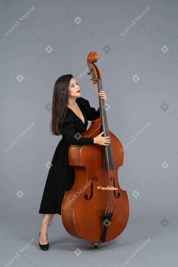 一位年轻女士穿着黑色连衣裙，靠在她的双低音上的全长