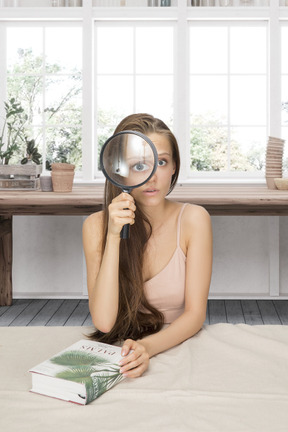 A woman sitting on the floor looking through a magnifying glass