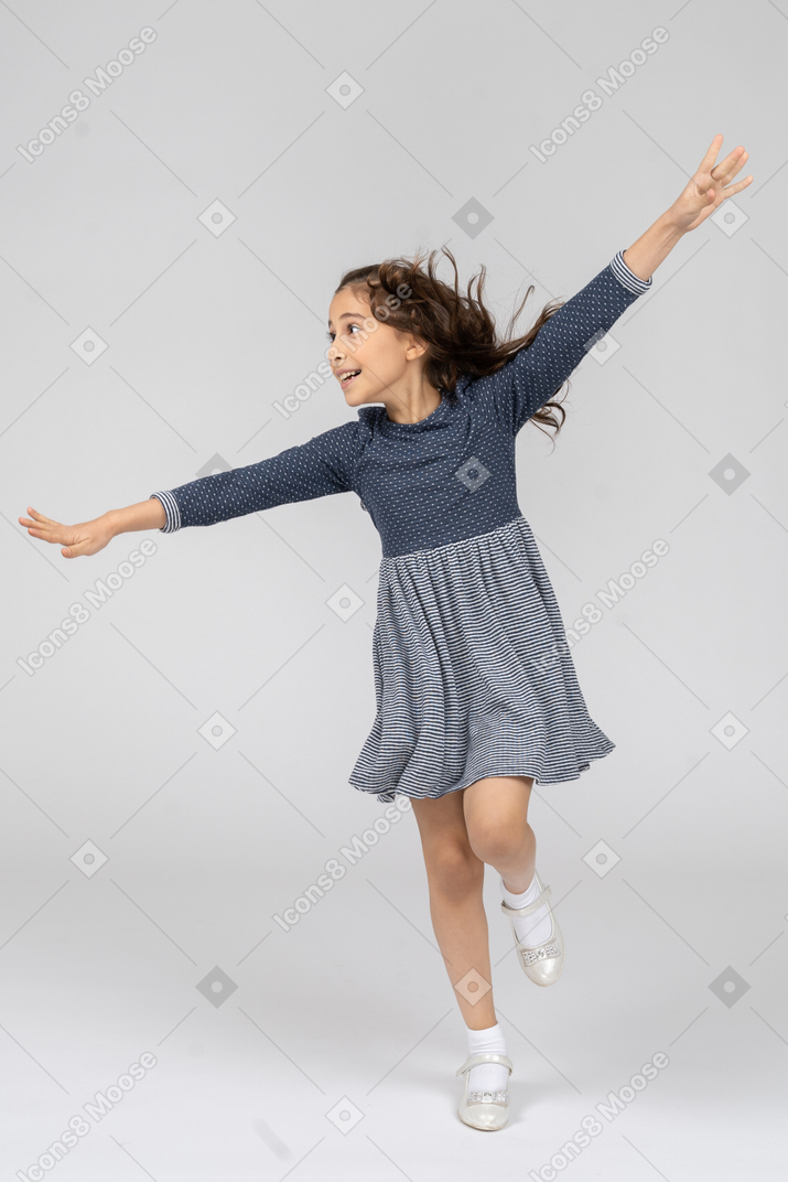 Front view of a girl running around imitating a plane