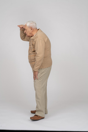 Side view of an old man in casual clothes searching for someone