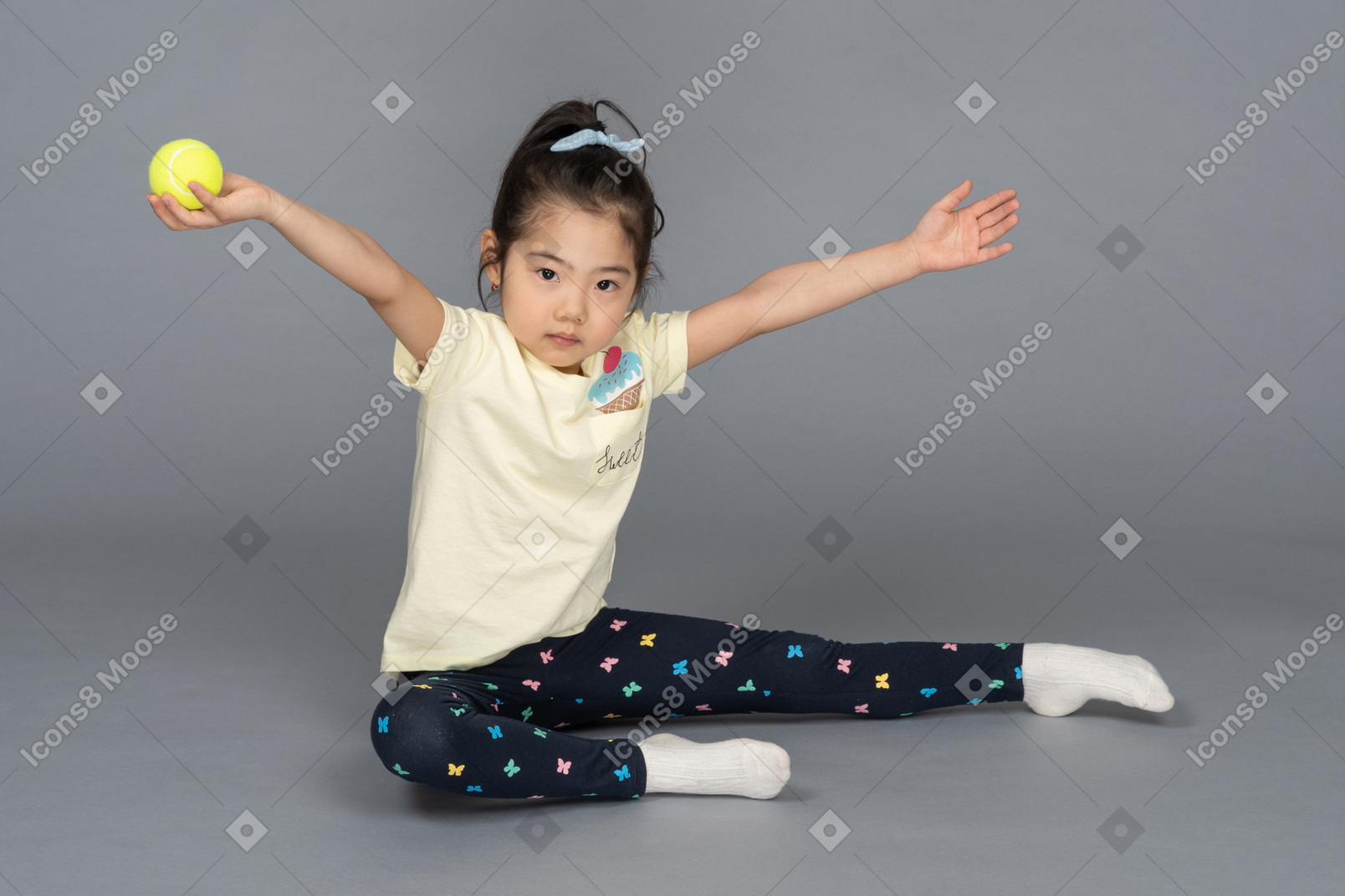 Girl with a tennis ball sitting on the floor