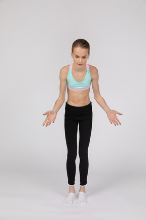 Side view of a teen girl in sportswear raising hand and arguing