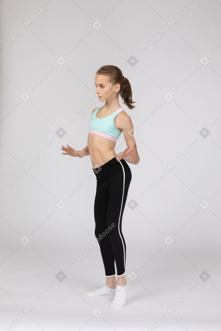 Vista de tres cuartos de una jovencita en ropa deportiva bailando mientras gesticula