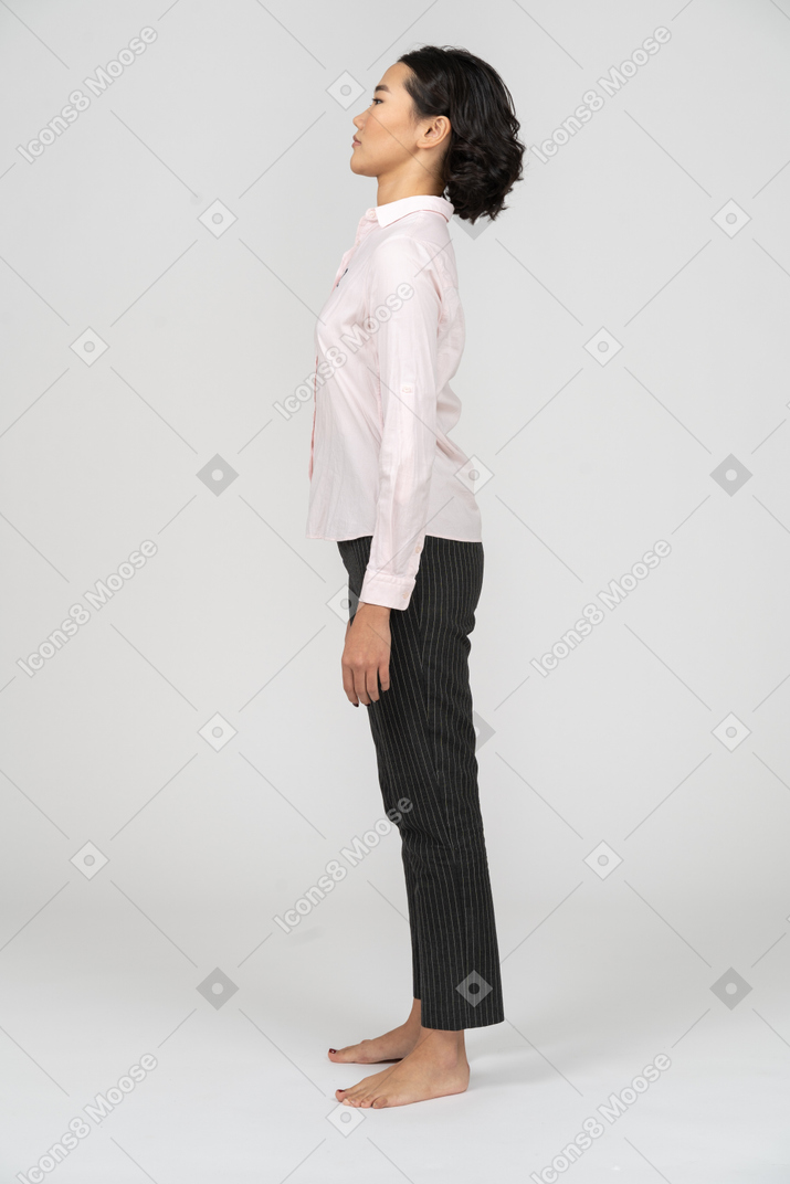 Side view of a woman in office clothes standing with arms at sides