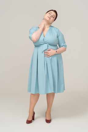Front view of a woman in blue dress touching her neck
