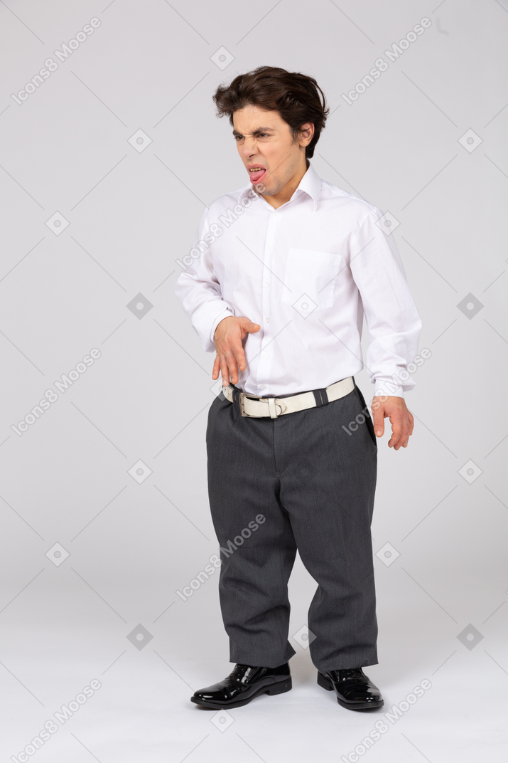 Young man making disgusted face and sticking out tongue