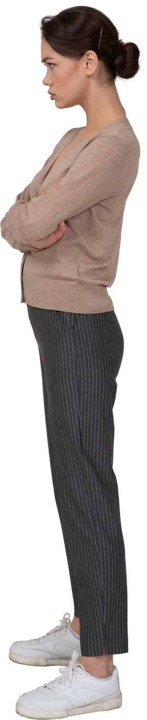 Vista laterale di una giovane donna offesa in pullover e pantaloni che attraversano le mani