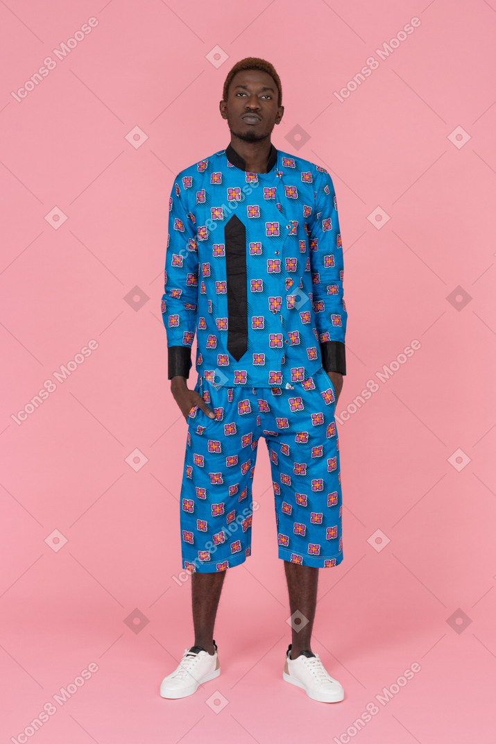 Hombre negro en pijama azul de pie sobre fondo rosa