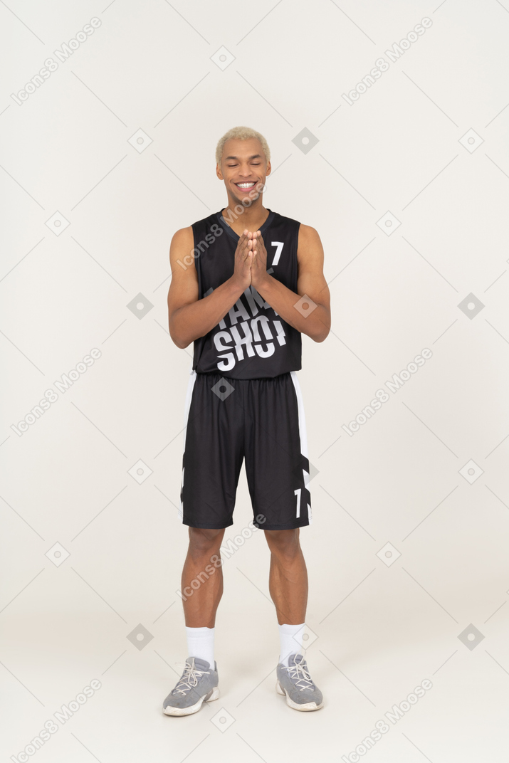 Vista frontale di un giovane giocatore di basket maschile sorridente che si tiene per mano insieme
