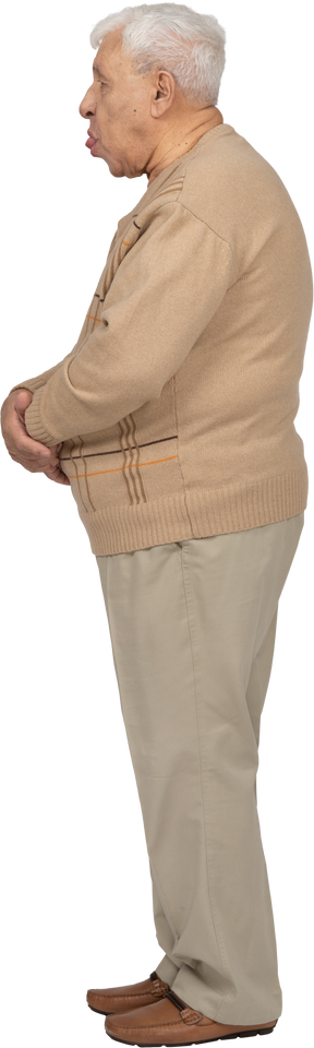 Vista laterale di un uomo anziano in abiti casual che mostra la lingua