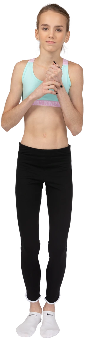Front view of a perplexed teen girl in sportswear touching her hands