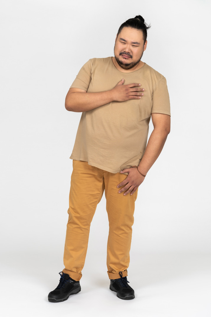 Sad asian man standing with hand on his chest