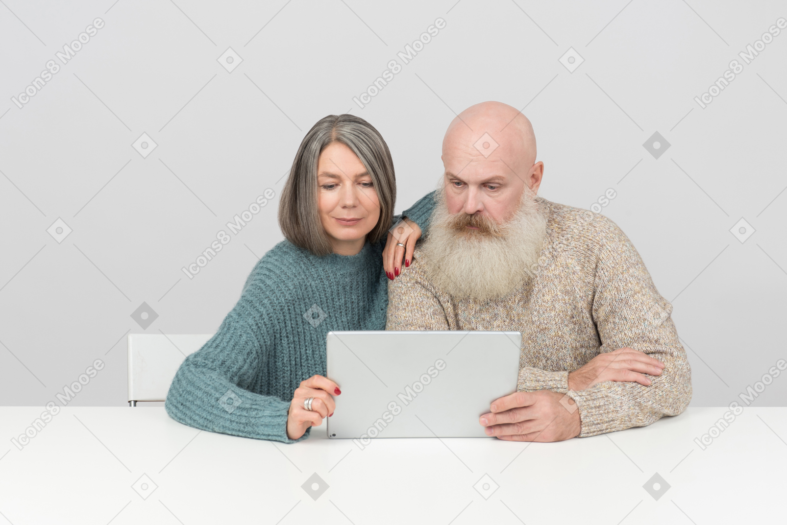 Couple âgé assis à table et regardant une tablette numérique