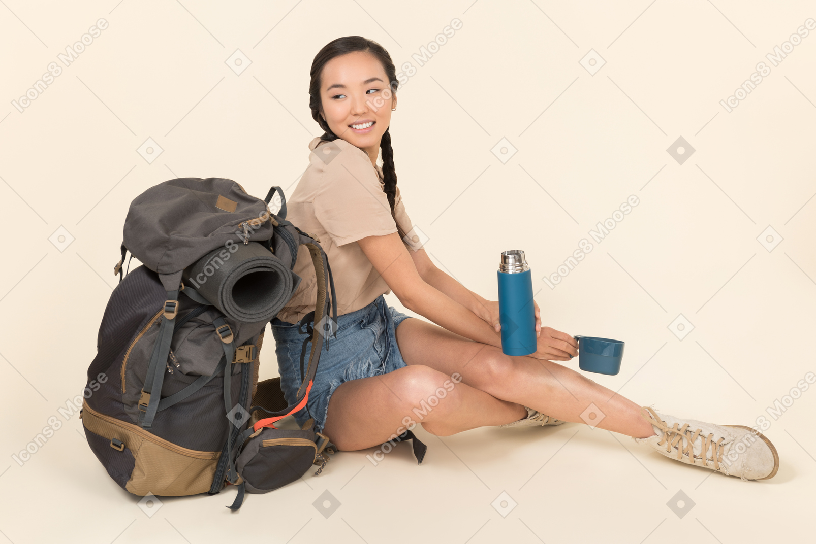 年轻的亚裔女子坐在靠近背包和处理热水瓶
