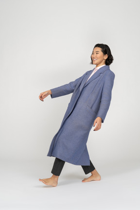 Smiling woman in coat leaning backwards