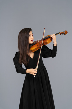 Close-up de uma jovem de vestido preto tocando violino