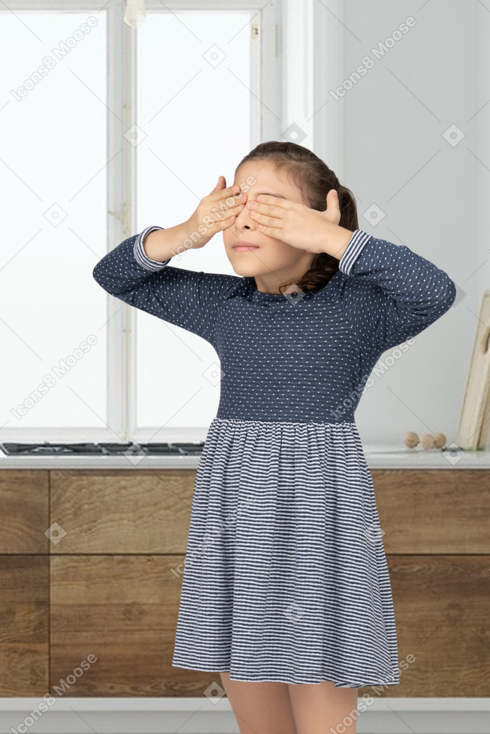 Girl standing and covering her eyes
