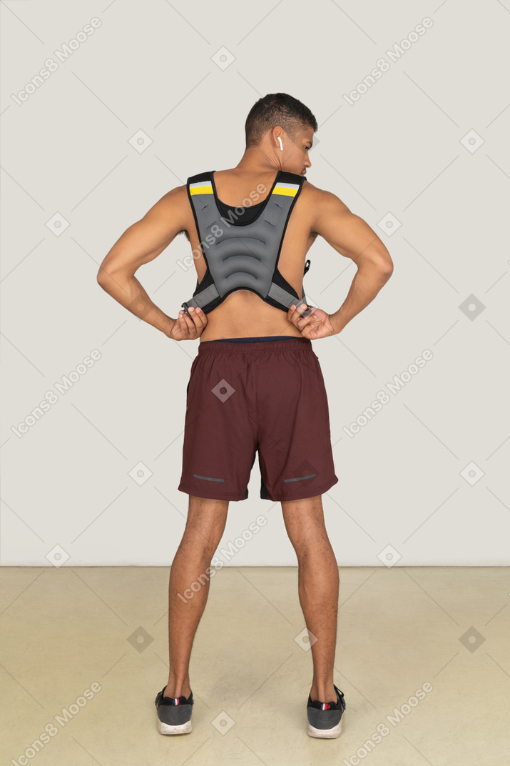 A back side view of the muscular man wearing a life vest and looking right