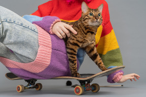 Une fille et un chat assis sur une planche à roulettes