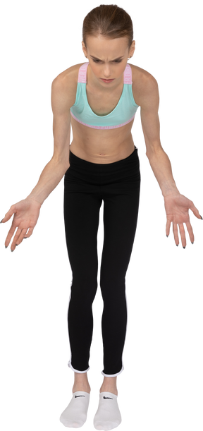 Front view of a teen girl in sportswear outspreading hands and looking down