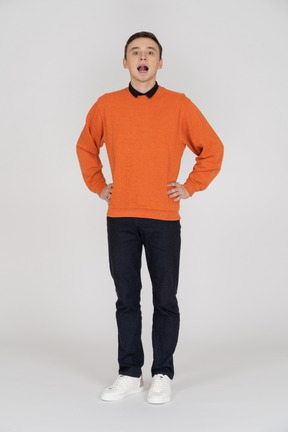 立っているオレンジ色のセーターを着た若い男