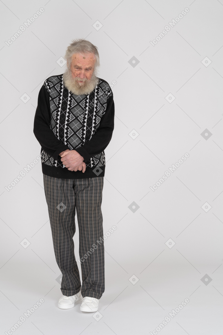 Пожилой мужчина стоит со сложенными руками и смотрит вниз