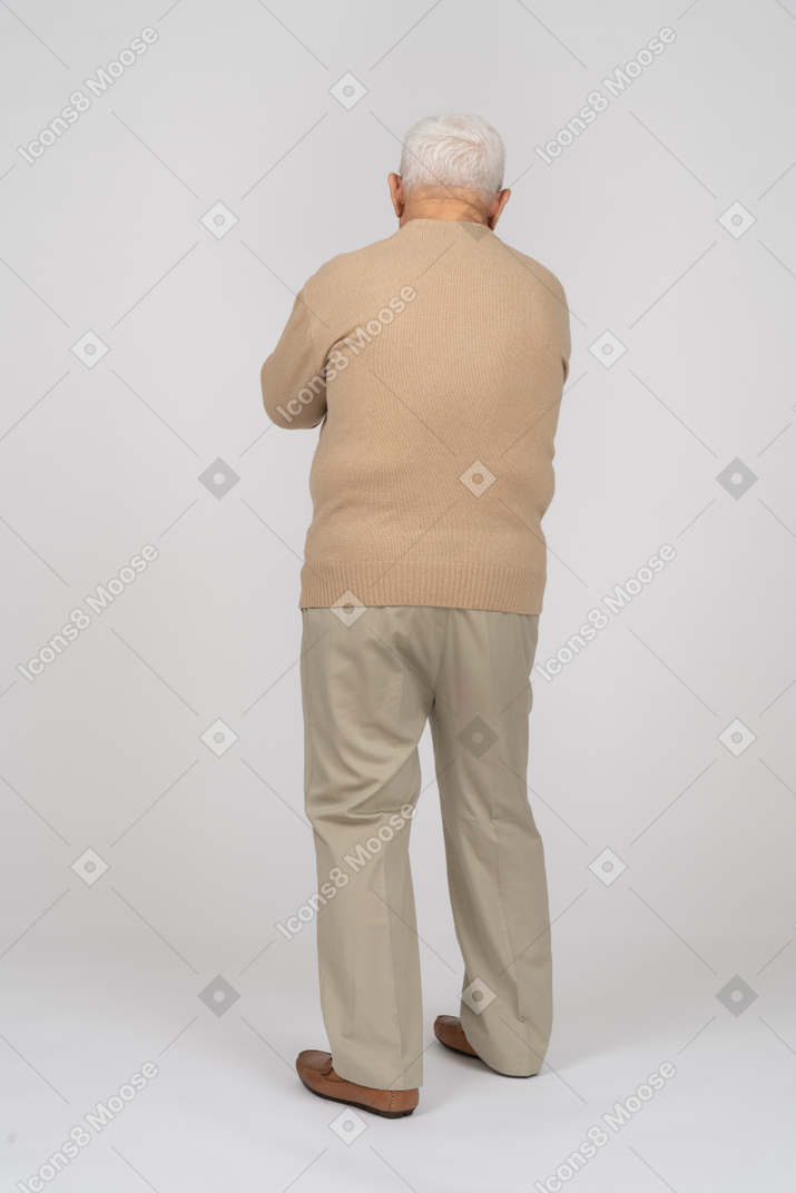 カジュアルな服を着て歩いている老人の背面図