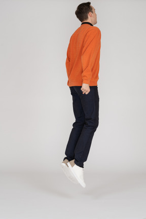 Junger mann im orange sweatshirt springen