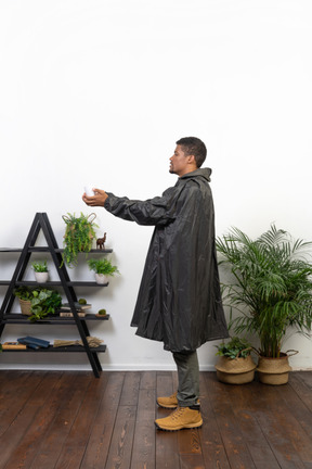一个穿着雨衣的男人捕捉雨滴的侧视图