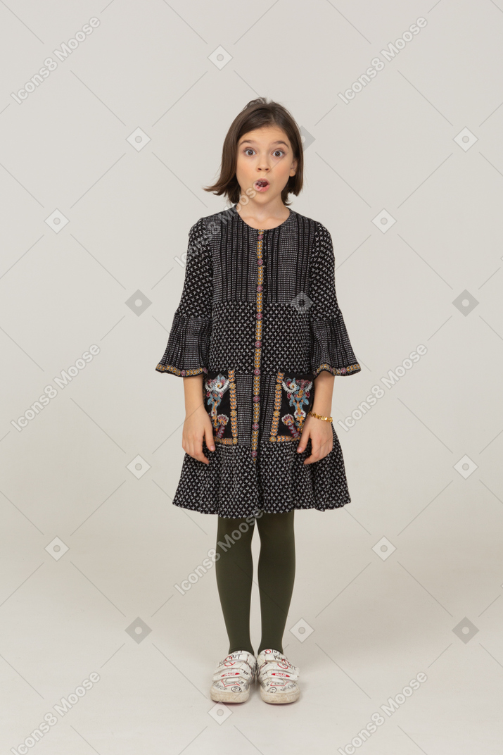 Front view of a shocked little girl in dress looking at camera