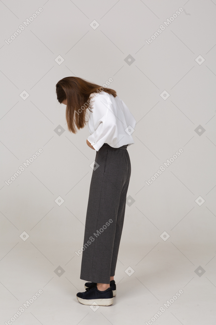 Side view of a young lady in office clothing adjusting her pants