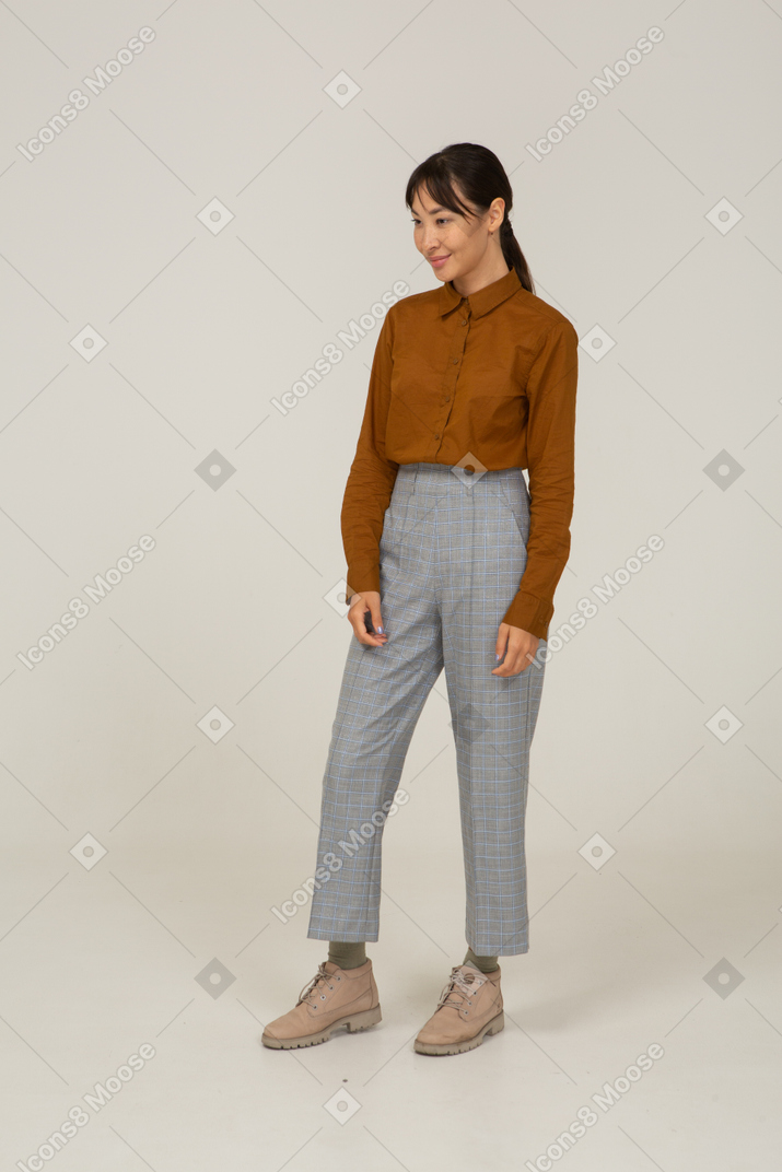 Vista de tres cuartos de una mujer asiática joven sonriente en calzones y blusa