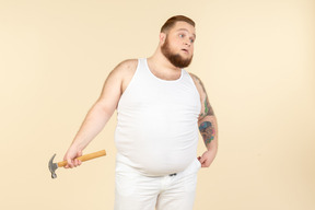 Emotional young big guy holding hammer