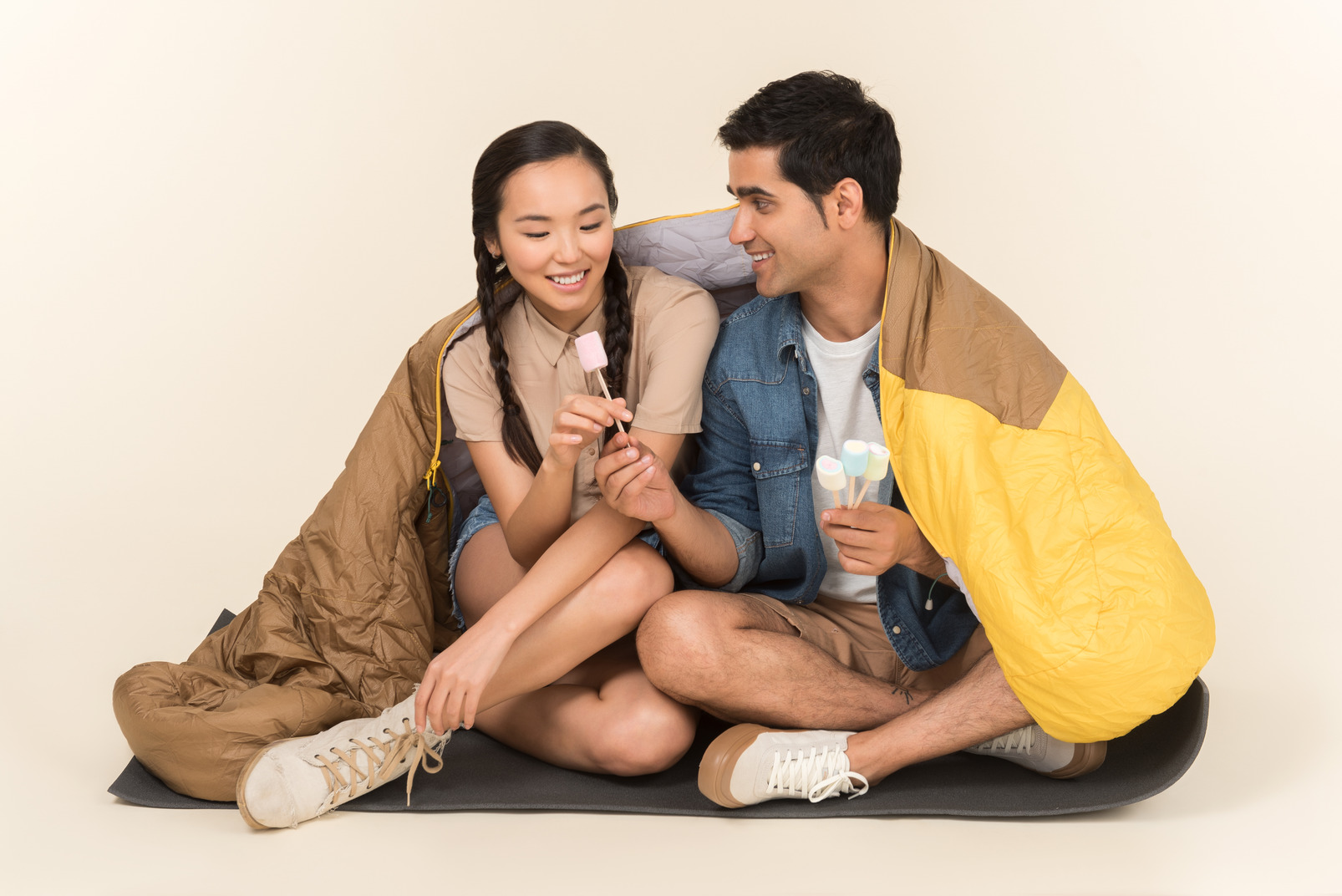 Laughing young interracial couple holding marshmallows