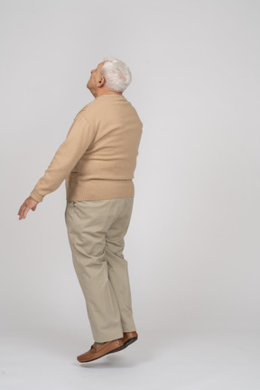 カジュアルな服を着てジャンプする老人の側面図