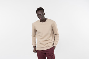 A young black man in a grey sweater standing alone on the white background