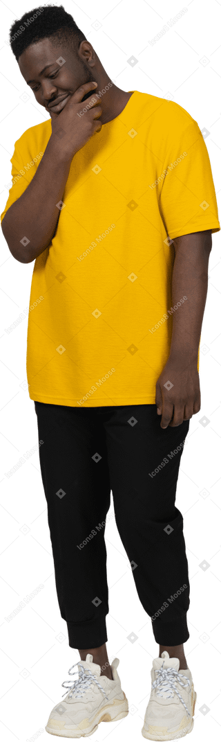 턱을 만지는 노란색 티셔츠를 입은 짙은 피부의 젊은 남자의 4분의 3 보기