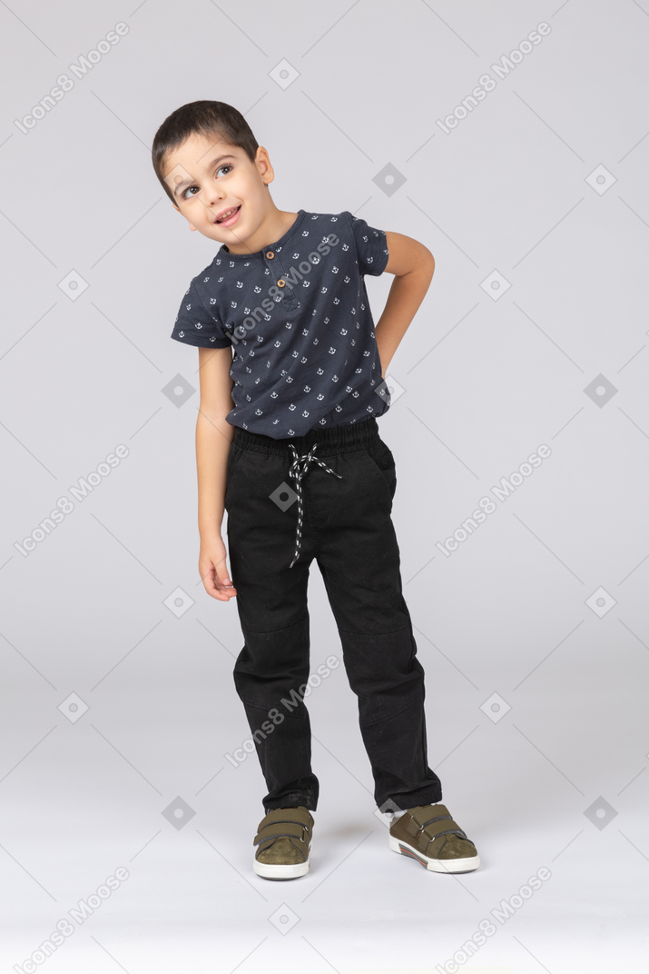 Front view of a cute boy standing with hand on back