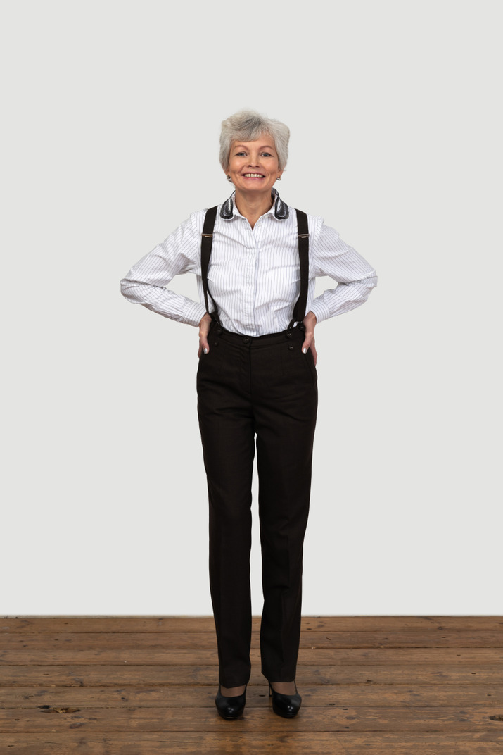 Full-length of a delighted old female in suspenders putting hands on hips