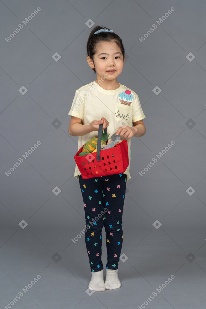 Front view of a little girl holding a shopping basket
