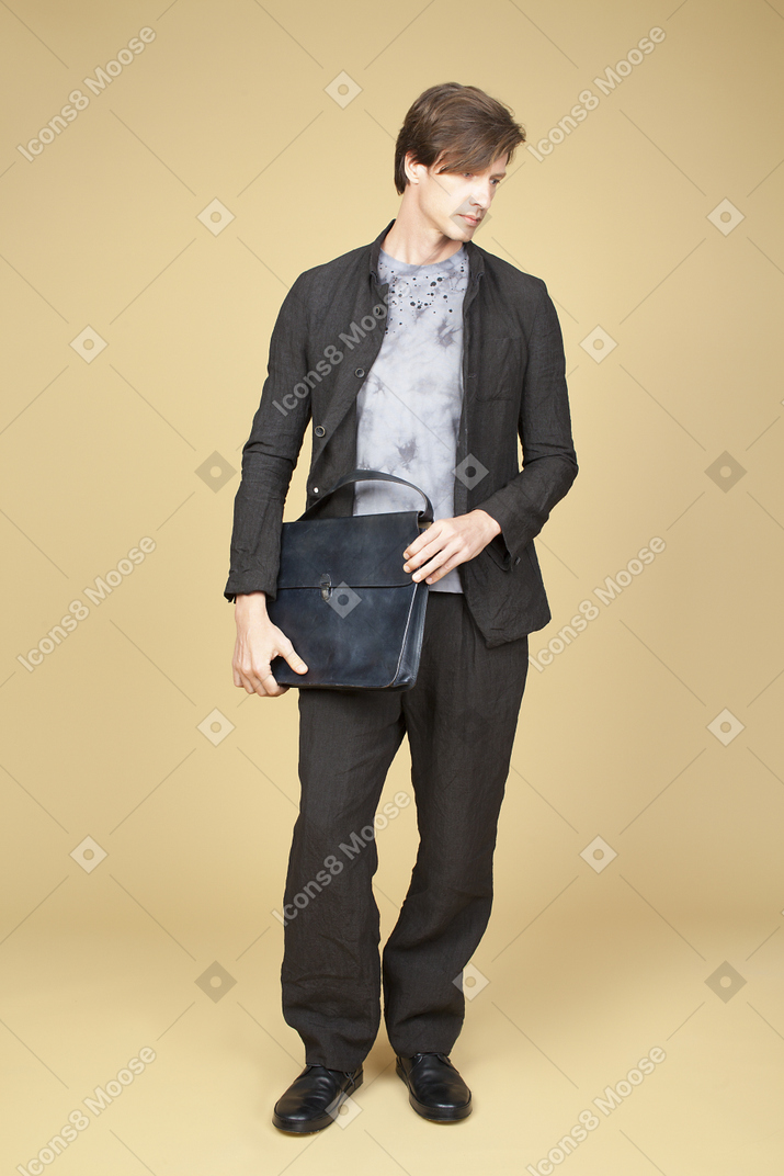 Handsome man in black suit holding a black bag